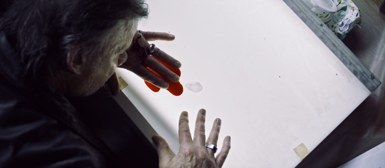Jerome R Marzullo holding a crystal while sitting at a bright table in warehouse setting.