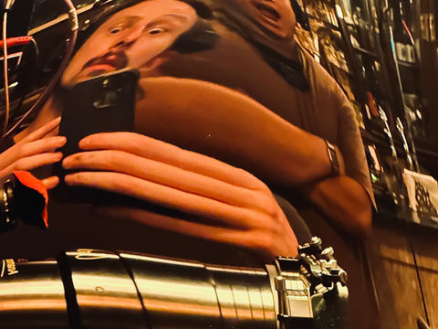 Film crew member holding a phone near a cinema camera rig during filming.