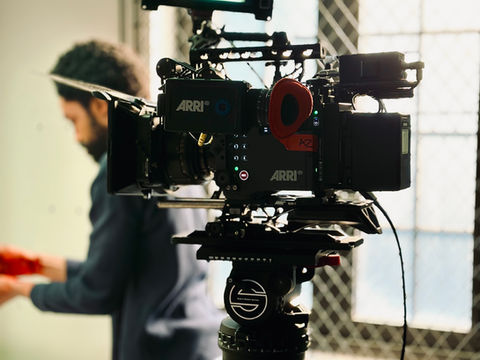 Cinema camera in foreground filming actor Perry James Howell preparing an object during a scene in Deep music video.