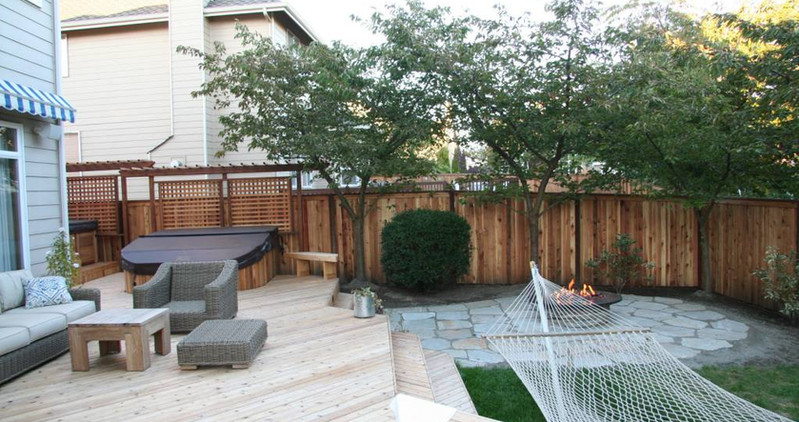 Beautiful custom backyard builds by Decks and Spas featuring deck and hot tub, privacy screen, BBQ centers, and firepits. Composite decking. Located in Redmond, Serving the Eastside, and Greater Seattle.