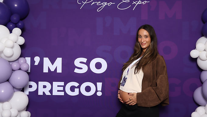 Three women smile holding beer signs before wooden backdrop at Montrose Craft Beer Fest.