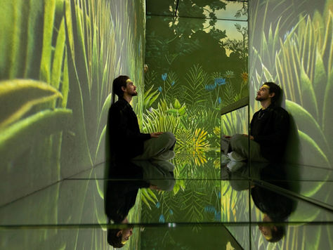 a man sitting down in a. green room with art
