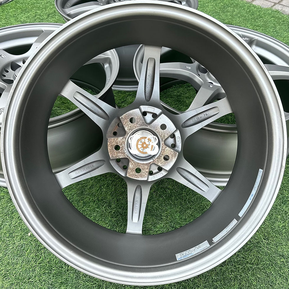 الصورة المصغرة: Close-up of a silver alloy wheel, RAYS VR CE28, on a green surface