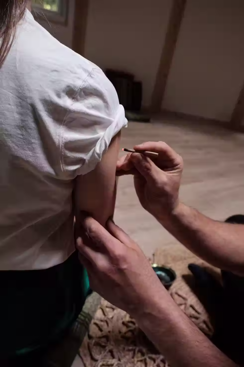 Practitioner applying dots with a bamboo stick, preparing for Kambo dots