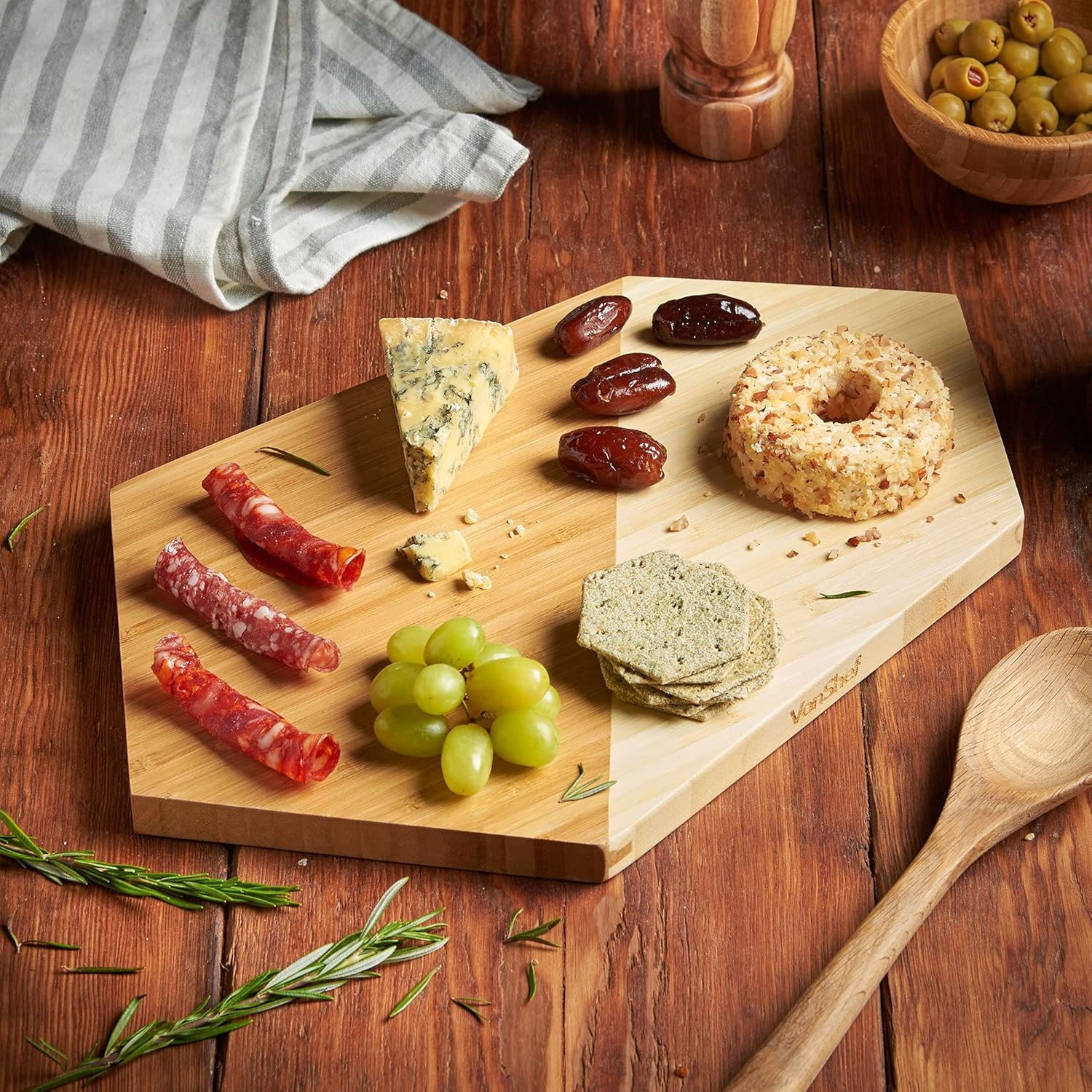 Wooden cheese board with assorted cheeses, grapes, and dates