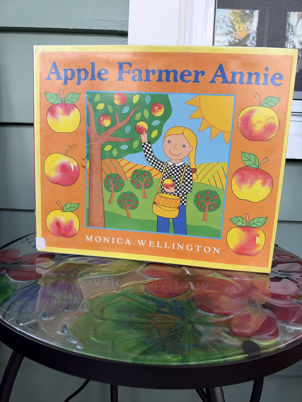 Apple Farmer Annie by Monica Wellington, the picture book cover standing on a small table
