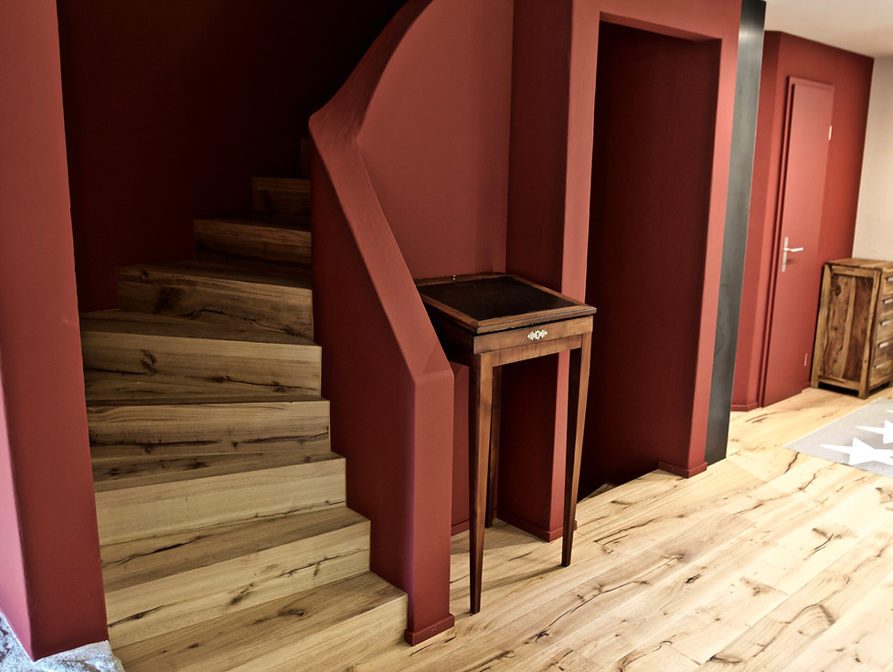 Umbau Wohnzimmer und Eingangsbereich mit Treppen. Wände und Decke in Naturpigmentfarben gestrichen. Boden in rustikaler Eiche geölt. Die Möbel kommen wunderbar zur Geltung. Garderobe in Schwarzstahl mit Zunderschicht verkleidet.