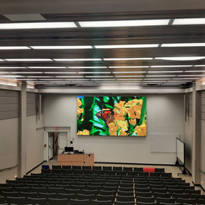 Large LED Video wall at the front of a university lecture hall other monitors are hung on the sides of the hall.