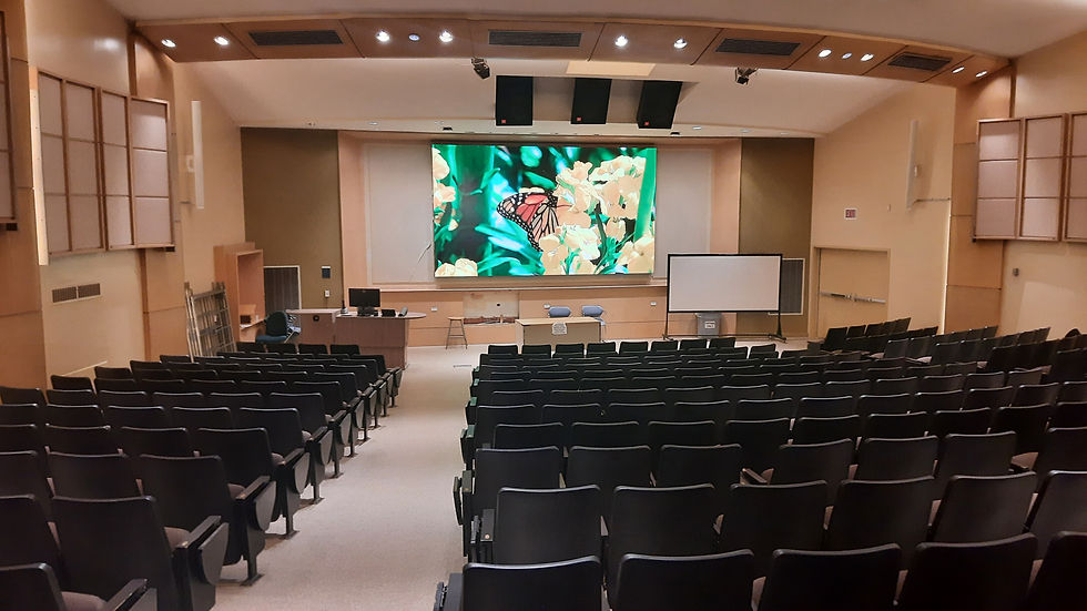 An image of a university Lecture Hall with a large video wall and speakers
