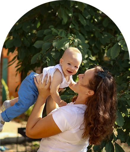 A smiling mother playfully lifts her joyful baby.
