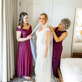 Brides family helping her put her dress on.