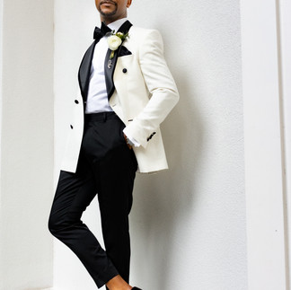 Groom leaning on wall at hotel.