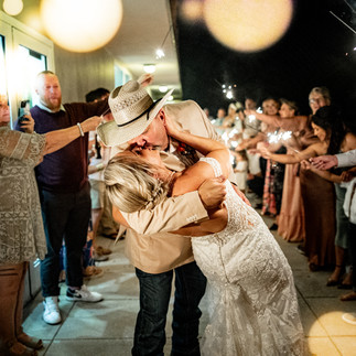 Bride and groom kissing during sparkler exit.