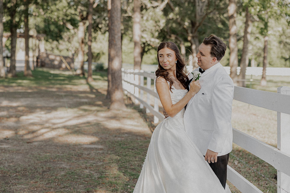 Bride and groom holding each other on fence.