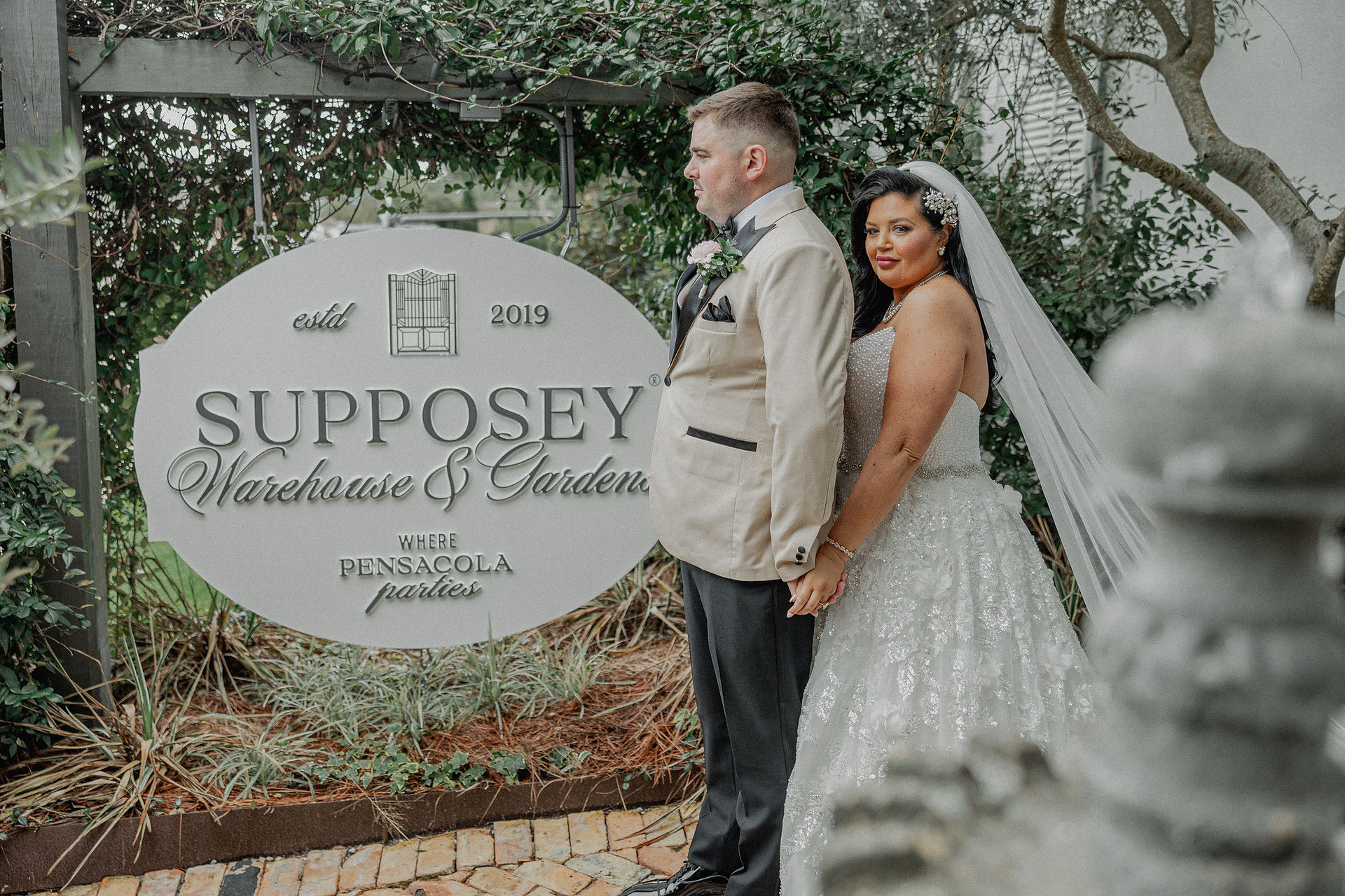 Bride holding groom in front of Supposey sign