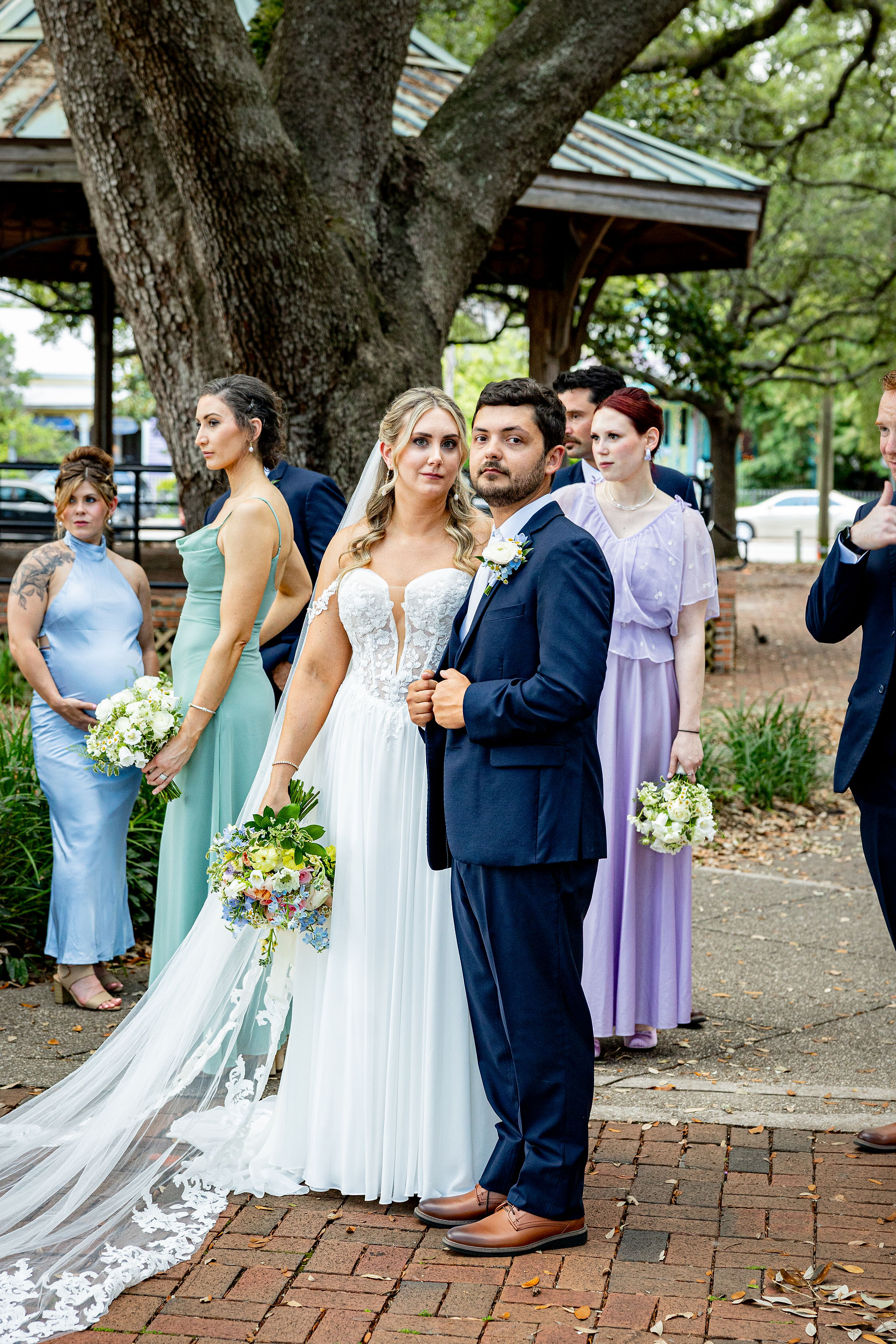 Bride and groom standing together in park.