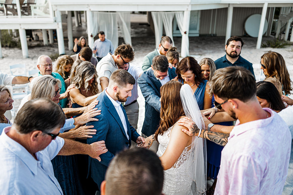 Family and friends praying over bride and groom.