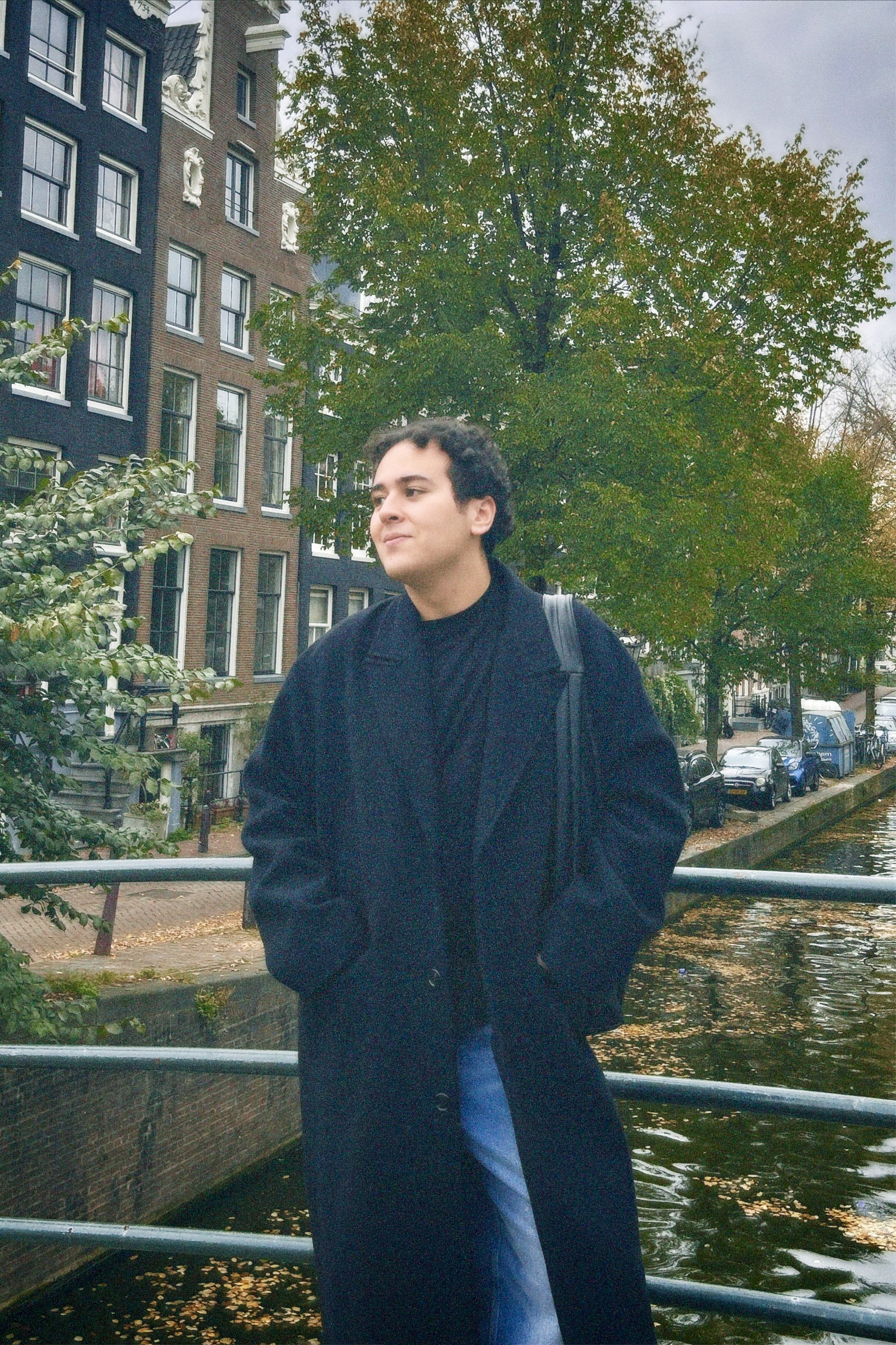 Portretfotografie van Yousri Adam op een brug in Amsterdam, met grachten, historische architectuur en herfstkleuren.