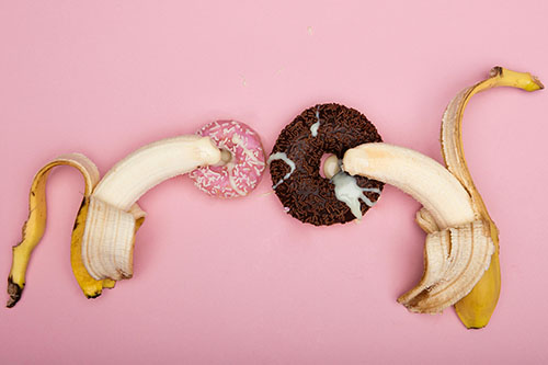 An image with two bananas inserting into a doughnut. Representing insertive and receptive sex.  
