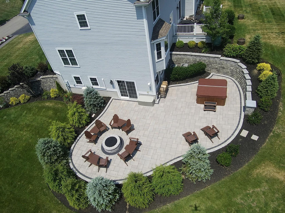 Aerial view of a custom stone patio with fire pit and hot tub.