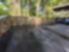 Natural stone retaining wall along an asphalt driveway