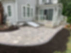 Curved paver patio by a house with fresh mulch edging.