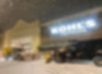 Snow plows clearing a Kohl's Sephora parking lot at night.