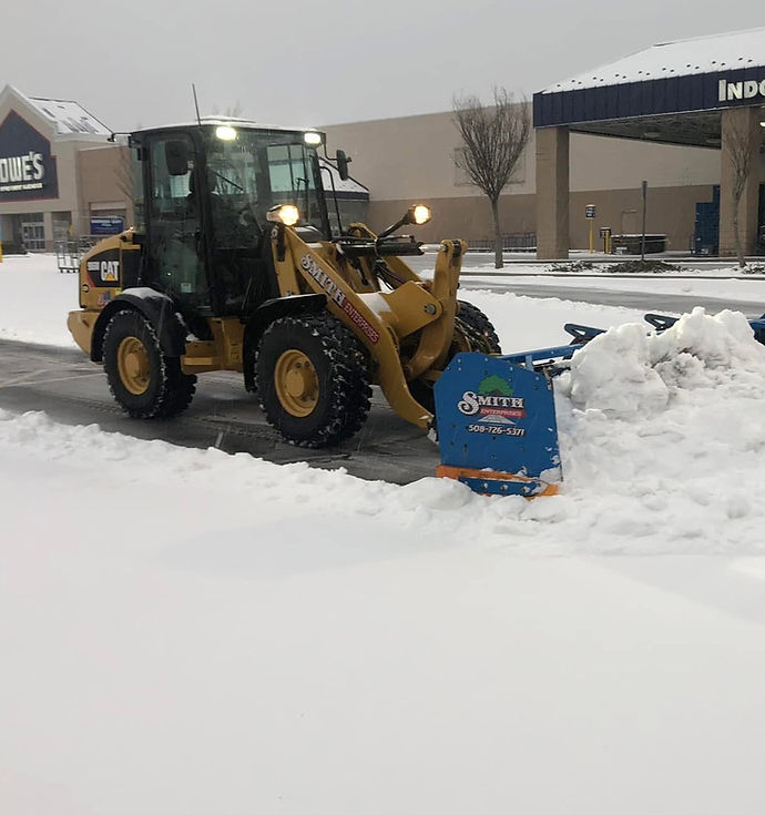 Frontend loader clearing snow at a commercial lumber yard.