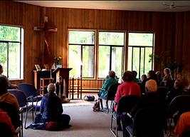 A warmly lit room with people sitting and meditating together