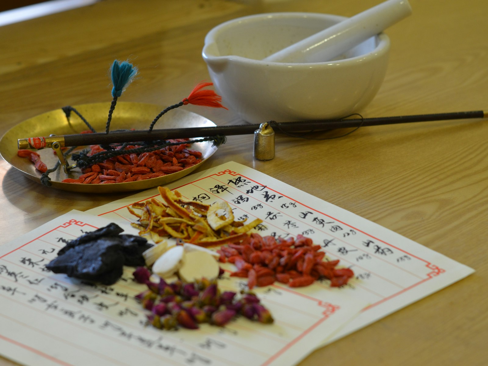 Chinesische Heilkräuter, Schale und Rezeptbuch auf Holz