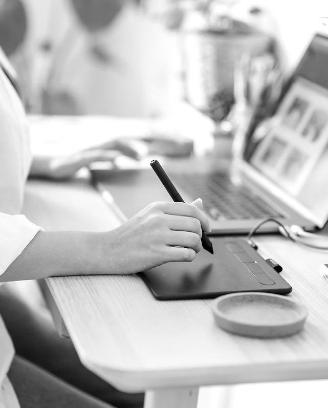 A girl holds a pen over a notepad.