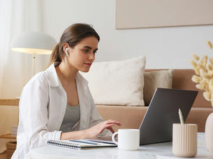 A woman works on her laptop in her living room.