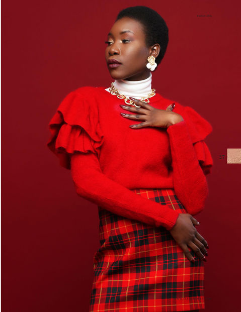 Bold glam makeup on a dark-skinned client, featuring a smooth matte base, defined eyes, and a deep berry lip, styled in a red outfit for a studio photoshoot.