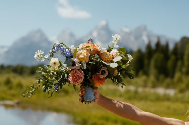 Lush bridal bouquet with green, white, peach, yellow, and blue flowers designed for a romantic elopement in the Tetons