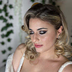 woman with blonde highlighted and curled hair posed looking down with shimmery winged eyeshadow