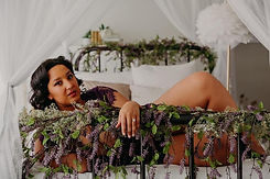 Beautiful woman laying on her side on an iron bed wrapped in purple flowers.