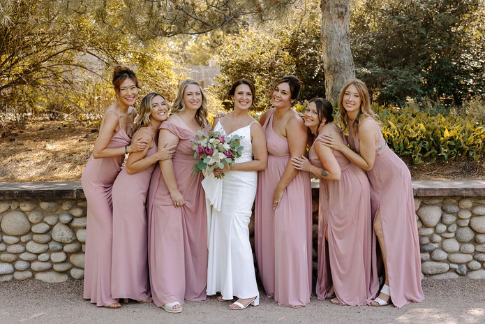 Bridesmaids in pink dresses with bride holding bouquet, wedding photo