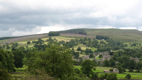 Waterfall and old packhorse bridge tucked among cottages in a quintessentially English village
