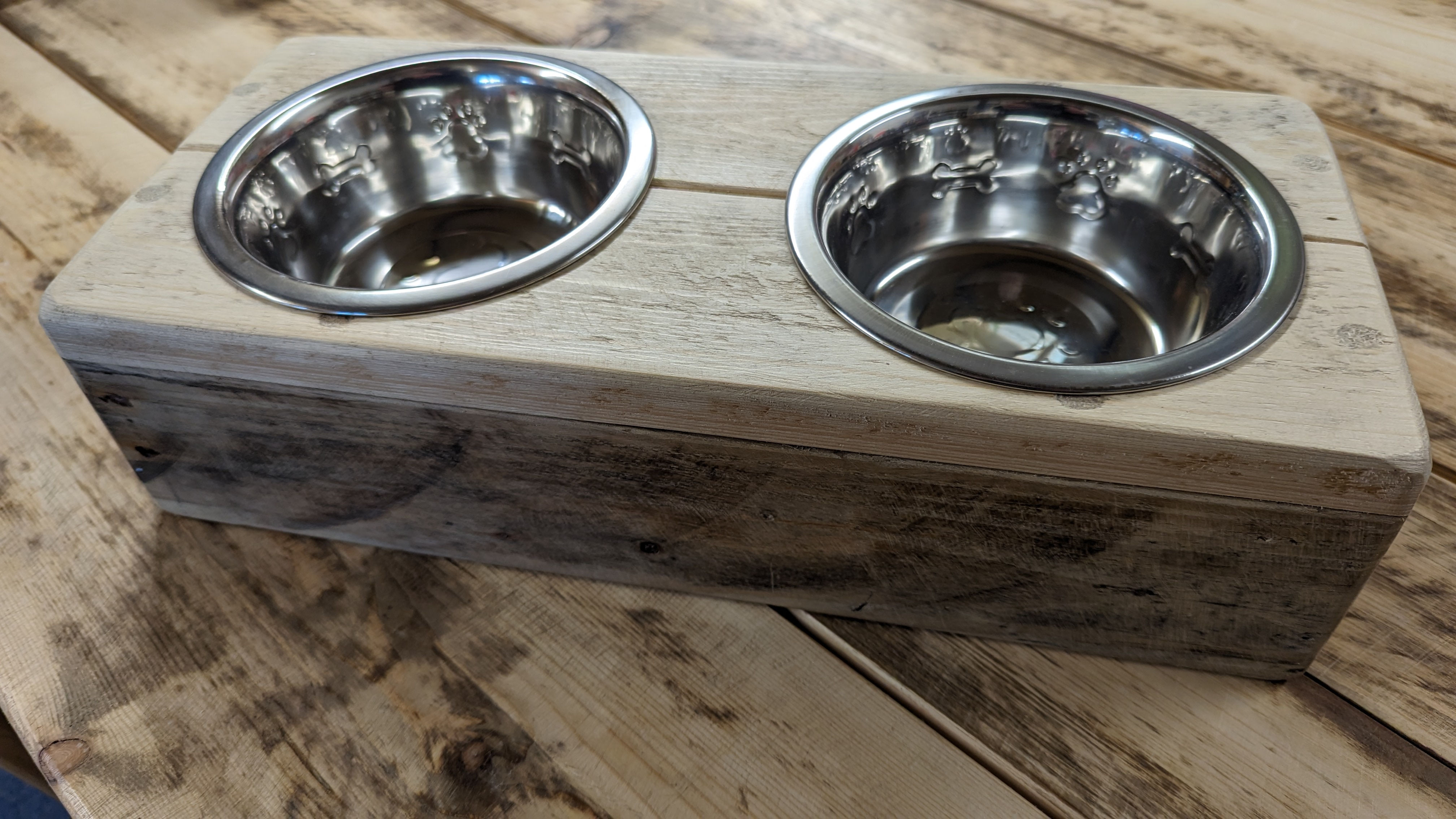Raised metal dog bowls on a wooden platform