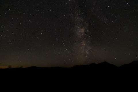 a starry night sky in Wales with mountains in the foreground
