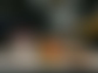 Coffee, a pot of fresh fruit, and a wholegrain sandwich placed on a table at a UK train station, with blurred trains and the station roof in the background, representing healthy eating while travelling.