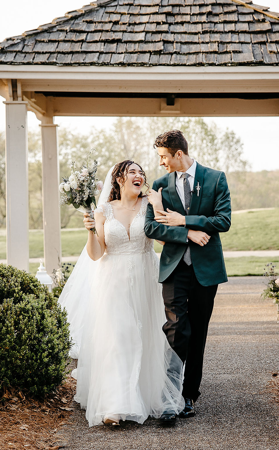 Happy newlyweds walking under a wooden gazebo at a Nashville wedding venue with natural surroundings.