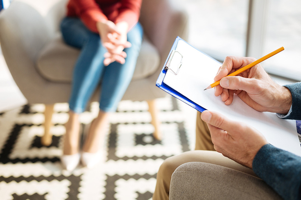 Stock Image of timid woman in therapy session and man with clipboard