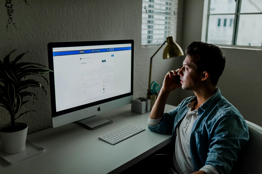 Stock image of man on phone staring at computer at work