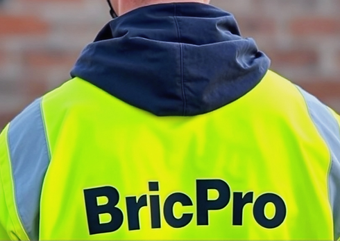Bricklayer located in Perth with his back to you in hi vis and white helmet. No wording on
