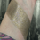 Thumbnail: Swatched gold highlighter product on wrist. Under the Moon - Gloomy Glow Highlighters - Vegan