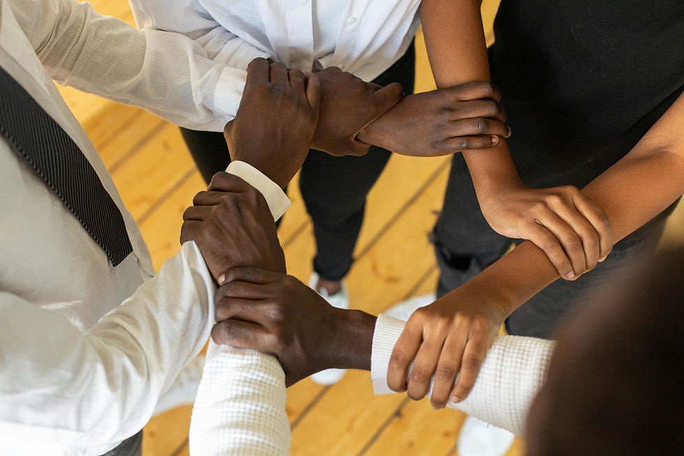 A close up image Black and brown hands form a circle by gripping a different wrist