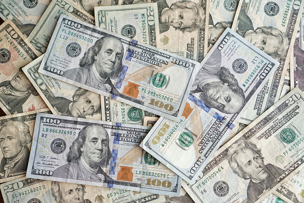 A pile of U.S currency with close up views of Ben Franklin, Alexander Hamilton and George Washington on them.