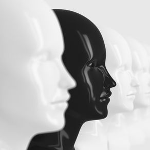 A row of identical white, and one black, mannequins form a line of about a dozen plastic faces
