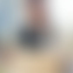 A young Black woman with braids wearing business attire carries a cardboard box with office supplies peeking out of it. 